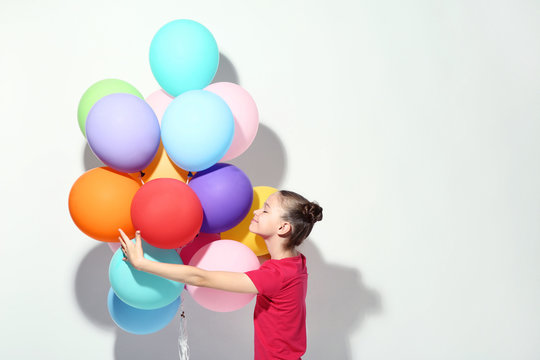 Beautiful young girl with colored balloons on white background