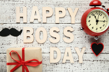 Inscription Happy Boss Day with alarm clock and gift box