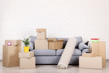 Cardboard boxes with household stuff and grey sofa on brick wall background - Powered by Adobe