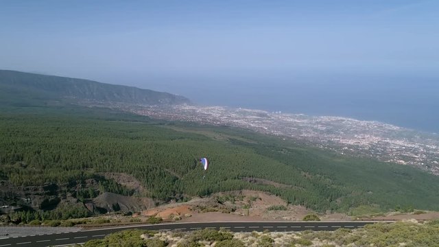 Aerial - Person paragliding over distant city