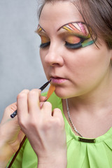 Closeup photo of professional makeup artist painting woman lips with brush. make-up for an artist.