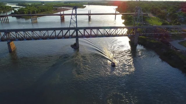 Boat going under a bridge at sunset in 4K