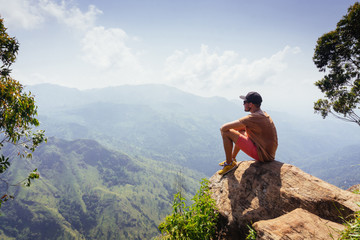 Naklejka na ściany i meble Travel concept. Male hiker on Ella Rocka enjoying mountain landscape, Sri Lanka.