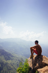 Travel concept. Man sitting on Ella Rocka enjoying mountain landscape, Sri Lanka