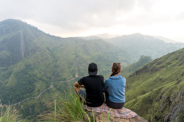 Naklejka na ściany i meble Travel concept. Couple sitting on top of Small Adams peak near Ella, Sri Lanka