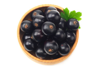black currant in wooden bowl with green leaf isolated on white background. top view