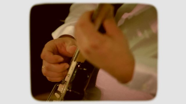 the hand touches the strings on an electric guitar. 8mm retro style film.
