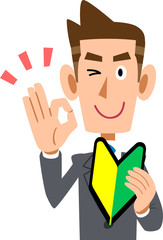初心者マークを左手に持ち、右手でOKのサインを示すビジネスマン
