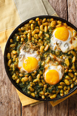 Iranian Baghali Ghatogh stew of beans and dill with fried eggs, garlic and turmeric close-up on a table. Vertical top view