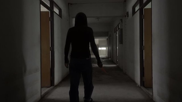 Silhouette of a man carry a knife walking in an Abandoned house
