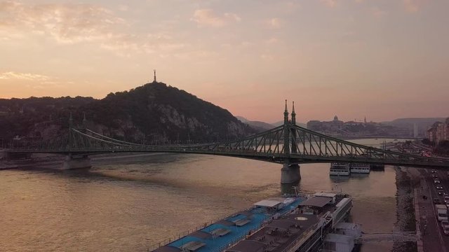 aerial drone footage of the liberty brindge in budapest at sunset with thee gell  rt hill in the background