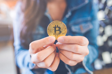 The hand of a woman holding a currency, bitcoin.