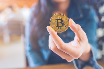 The hand of a woman holding a currency, bitcoin.