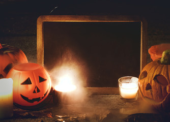 Halloween pumpkins and candles with blackboard