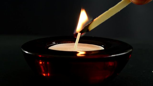 igniting fire on candle with match in dark room