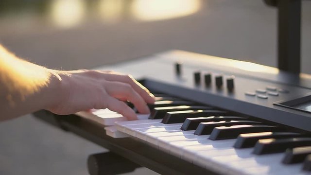 Close up fshe plays the synthesizer at sunset. FHD.