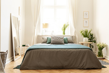 Beige, green and gray bedroom interior in a tenement house with a bed against a sunny window and...