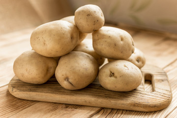 Raw potato tubers on a wooden background.