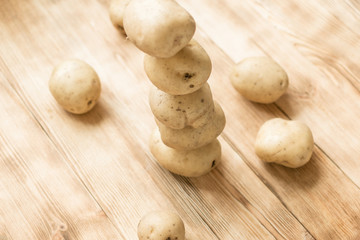Raw tubers of potatoes in the form of a pyramid on a wooden background.