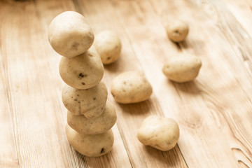 Raw tubers of potatoes in the form of a pyramid on a wooden background.