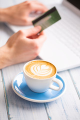 Female hand holding credit card using laptop.