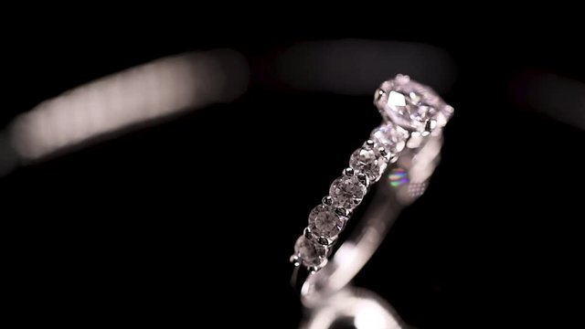 Engagement diamond ring rotating on black background, macro with shallow DoF