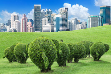 The tree is trimmed to the shape of elephants on green lawn outside the big city to add oxygen to the city, concept of save the earth and environment with environmental protection trap