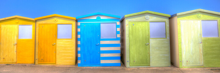 Beach huts bright colours with green blue and yellow colours and blue sky panoramic view in colourful HDR