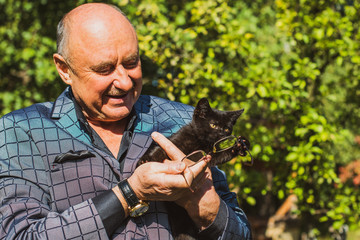 Active smiling senior man with a little cat, modern pensioner life. Mature man lifestyle, positive...
