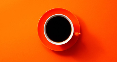 From above view of cup with black coffee placed on orange background - obrazy, fototapety, plakaty