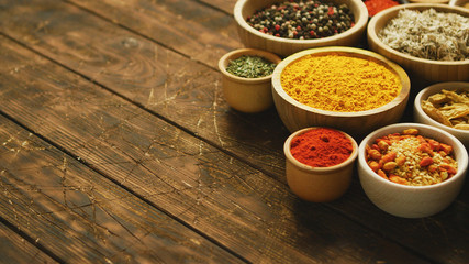 Collection of various spices and condiments in small bowls arranged on shabby wooden table