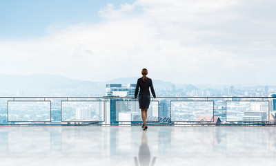 Sunrise above skyscrapers and businesswoman facing new day