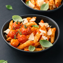 Tasty tomato pasta in bowl on dark