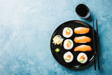 Sushi served on black plate on blue table