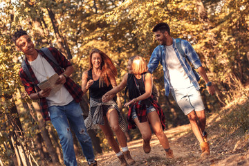 Group of four friends hiking together through a forest.