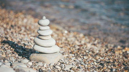 Fototapeta na wymiar Stones piramide on pebble beach - harmony, meditation, patience and peace of mind concept