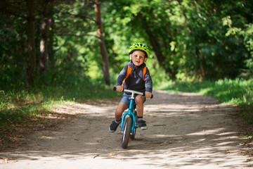 Toddler riding a balance bike along the path in the park