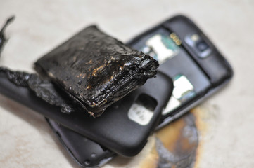 Mobile phone battery explodes and burns due to overheat. Danger, exploded mobile phone battery © Ivan