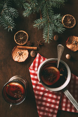 Obraz na płótnie Canvas top view of traditional christmas mulled wine with spices on wooden background with fir branches