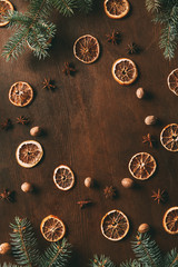 top view of dried orange slices, anise stars and nutmeg seeds on wooden background with pine branches for christmas