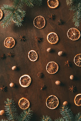 top view of dried orange slices, anise stars and nutmeg seeds on wooden background with fir branches
