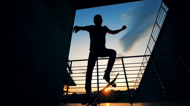 Skateboarder silhouette. Teenager skater lifts his board on a sunset background.