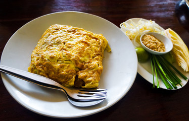 Egg wrapped pad thai on a plate in restaurant