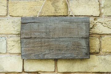 empty wooden board hanging on brick wall