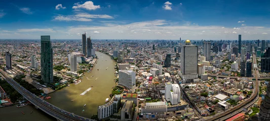  Aerial view of Bangkok skyline and skyscraper with BTS skytrain Bangkok downtown. Panorama of Sathorn and Silom business district Bangkok Thailand with blue sky and clouds. © Travel man