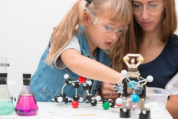 Science school, Museum of Science. A woman teacher and girl child collect molecules and conduct chemical experiments. On the table is a robot. STEM education. © AlesiaKan