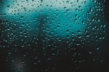 Raindrop on glass window, blue drops.