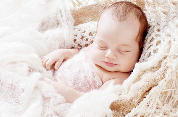 Beautiful little newborn boy 3 weeks sleeps in a basket with knitted plaid. Portrait of pretty smiling newborn boy