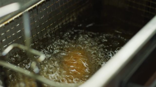 Close up shot of checking on food in a deep fryer by shaking it