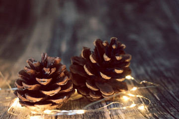 dark pine cone on wooden background with light string